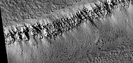 Close view of layers and boulders in the wall of a trough, as seen by HiRISE under HiWish program