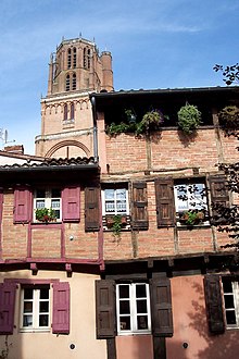 photographie d'une façade de maison en brique en encorbellement avec en arrière plan la cathédrale Sainte-Cécile