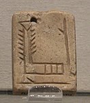 Etiqueta perforada mesopotàmica, amb el símbol "EN" què significa "mestre"; el revers de la placa té el símbol de la dea Inanna. Uruk, circa 3000 ae. Museu del Louvre, AO 7702