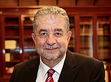 headshot photo of José Antonio Pascual, in a library wearing a suit and glasses