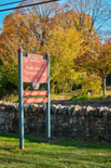 A rock wall and trees behind a large signpost