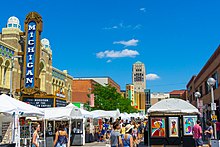 A photograph of a crowd of people walking between white tents at the Ann Arbor Art Fairs