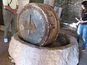 Moulin à triturer les olives - Nazareth L'Épart traversant l'œillard est maintenu par une cheville et permet de faire tourner la meule courante