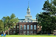 Four story red brick building with a white clock tower.