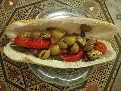 Sandwich filled with olives and sliced tomatoes