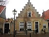 Pand met achterbouw, dwarsbouw en bijgebouw rond een door een muur van de straat afgesloten plaatsje met pomp