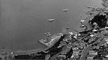 Aerial view of hills and coastline with flying boats.