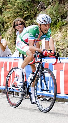 A man riding a bike while wearing a green uniform.