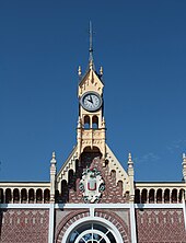 Gros plan sur le clocheton qui ornemente la façade du bâtiment voyageurs de la gare, par temps ensoleillé.