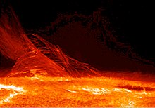 A photograph of the surface of the sun, with flares terminating from the surface on the left.