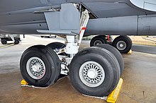 train principal d'un avion stationné. Les deux jambes portent chacune quatre roues. La boggie se trouve à l'extrémité d'un amortisseur, tenu en place par une bielle diagonale.