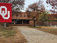 Front of Andrew M. Coats Hall with an OU banner on a pole to the left