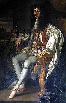 Seated man of thin build with chest-length curly black hair