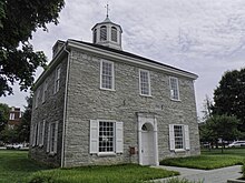 A two-story, federal-style grey brick building