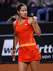 Une joueuse de tennis en combinaison orange serre le poing.