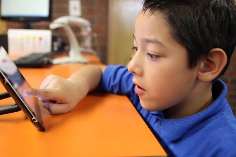 A young, male DPS student taking an electronic test. The boy looks like he is of early elementary school age.