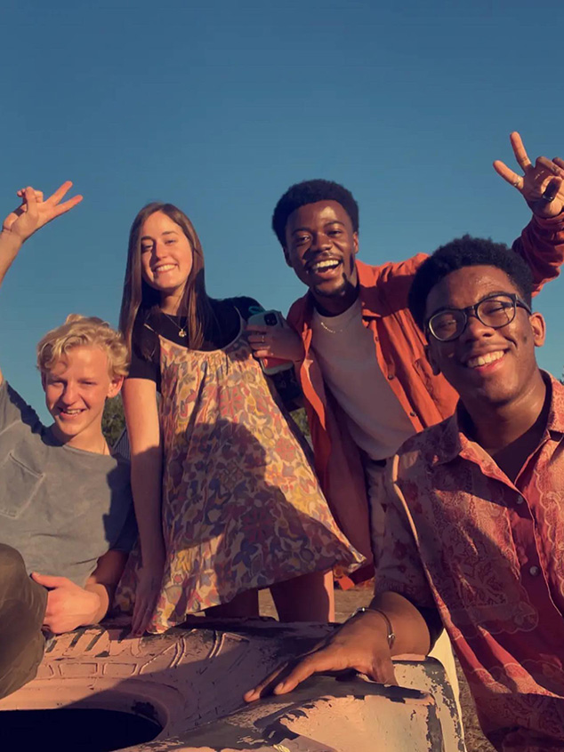 Four smiling people pose sharing peace fingers