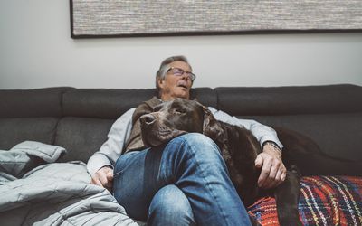 An older man sleeping with his dog