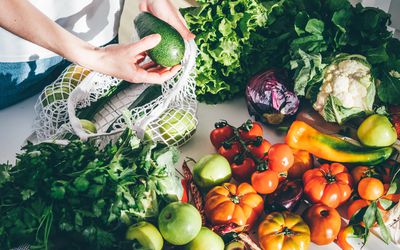 Woman takes fresh vegetables out of mesh bag 