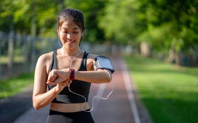 Young woman jogger ready to run set and looking at sports smart watch. 