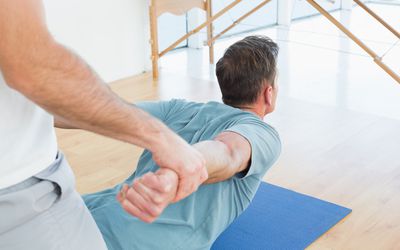 a therapist assisting man with stretching exercises