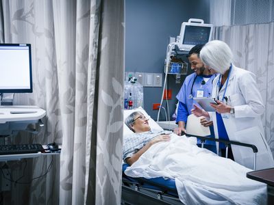 Doctor and nurse talking with patient in hospital bed