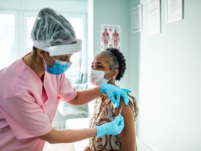 An older woman getting a vaccine from a healthcare provider in a doctor's office.