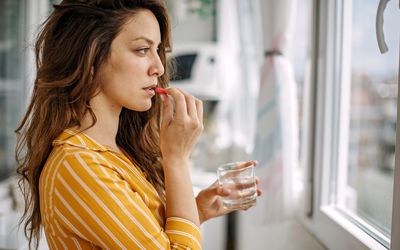 Young adult taking a supplement pill at home