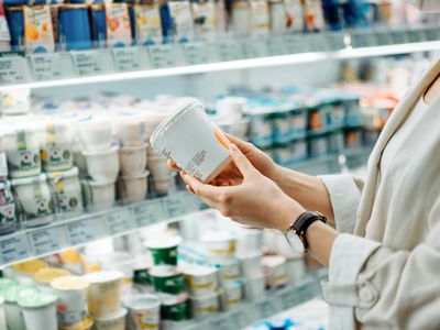 person holding yogurt container at grocery store