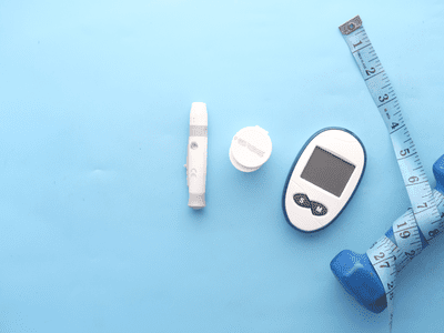 A glucose meter and test strips next to a hand weight and measuring table on a light blue background