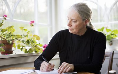 Woman at table writing down thoughts