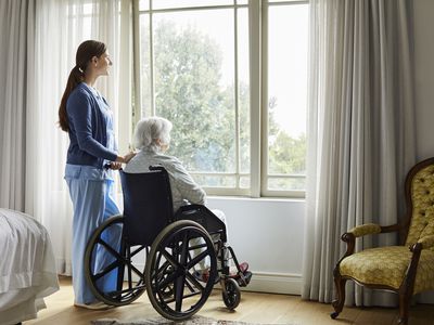 Caregiver with senior woman looking through window