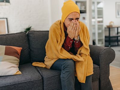 a man sneezing into his hands