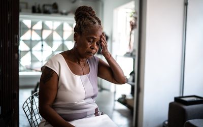 Mature woman with hand to head at home - stock photo