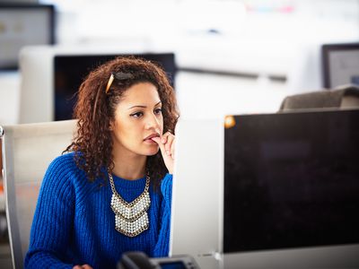 woman sitting at computer biting her nails; neurodivergence concept