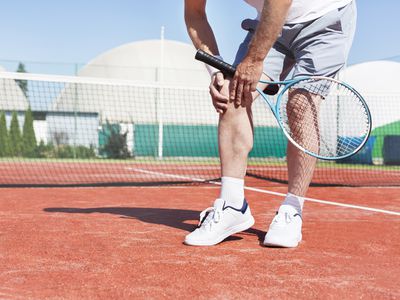 Tennis player holding knee in pain