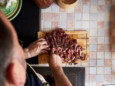 Close-Up Of high View of Man Preparing Tomakawk Steak On Cutting Board In A Kitchen