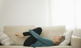 Photo of woman stretching her back on the couch.