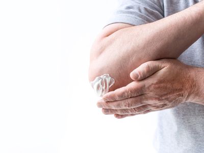 a man rubbing cream on his elbow