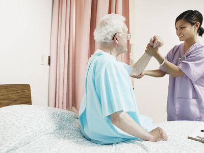 Hospice nurse helping male patient in bed