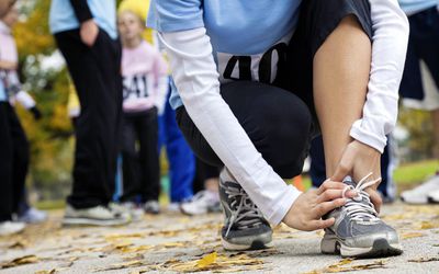 Woman holding her hurt ankle at a race.