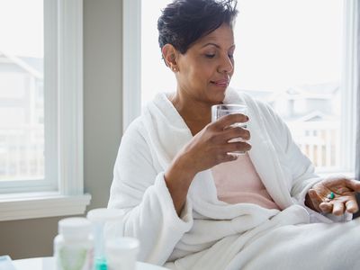 Woman in bathrobe taking vitamins