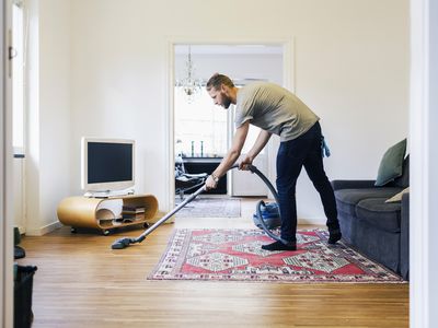 Side view of man vacuuming hardwood floor