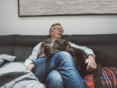 An older man sleeping with his dog