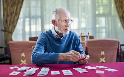 Senior man playing cards in nursing home