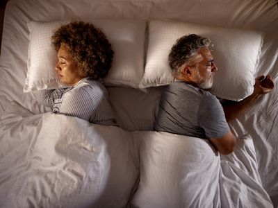 do women need more sleep than men? High angle view of relaxed senior couple sleeping back to back in a bed.