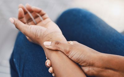 Hands, arm injury or pain of black woman after working hard in home or house interior. Hand, health and wellness of African female injured wrist after work on pc computer, carpal tunnel or arthritis.