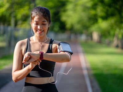 Young woman jogger ready to run set and looking at sports smart watch. 