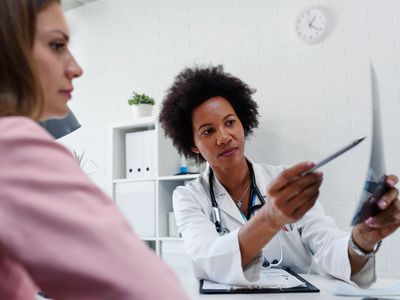 Doctor talking with patient at desk in medical office - stock photo