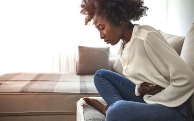 Woman sitting on bed and having stomach ache